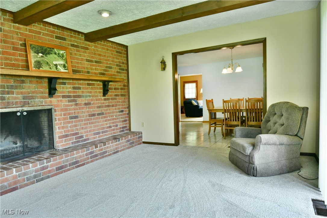 6509 Shaffer Road Northwest Warren, OH 44481 - Photo 26 of 50 Tiled living area with carpet flooring, a chandelier, baseboards, beamed ceiling, and a fireplace