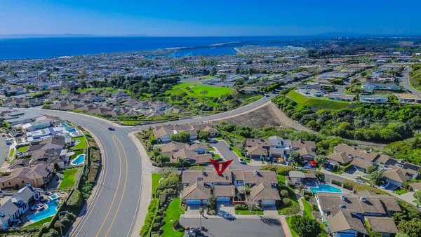 an aerial view of a city with lots of residential buildings ocean and mountain view in back