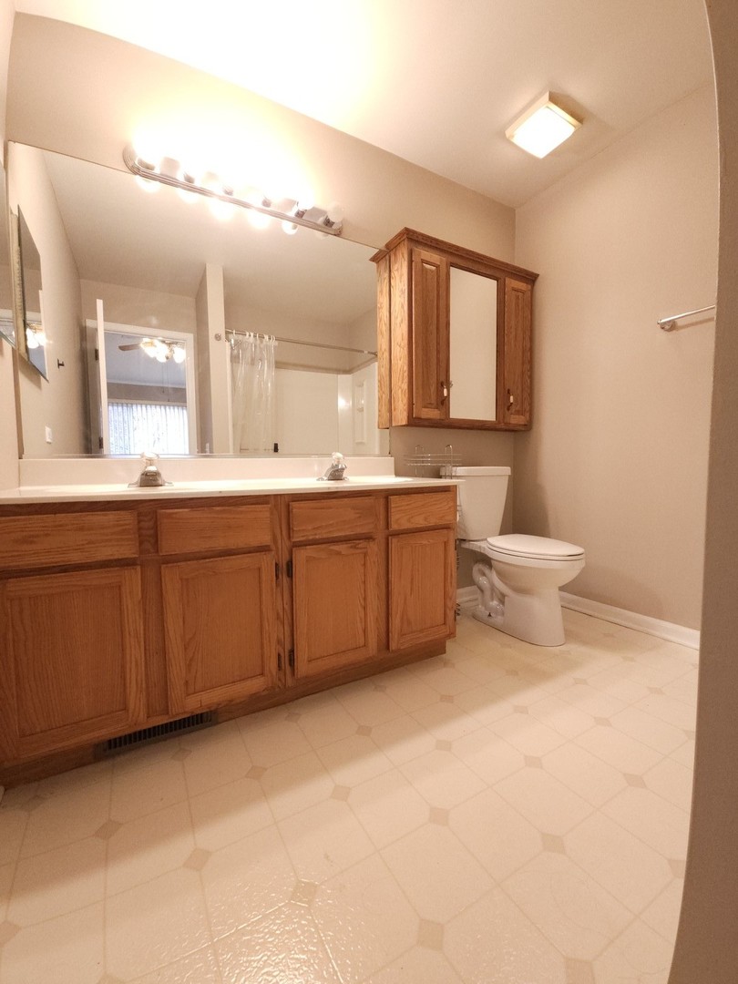 407 Spaulding Road, Unit 407 Bartlett, IL 60103 - Photo 11 of 18 a bathroom with a double vanity sink a toilet and a large mirror