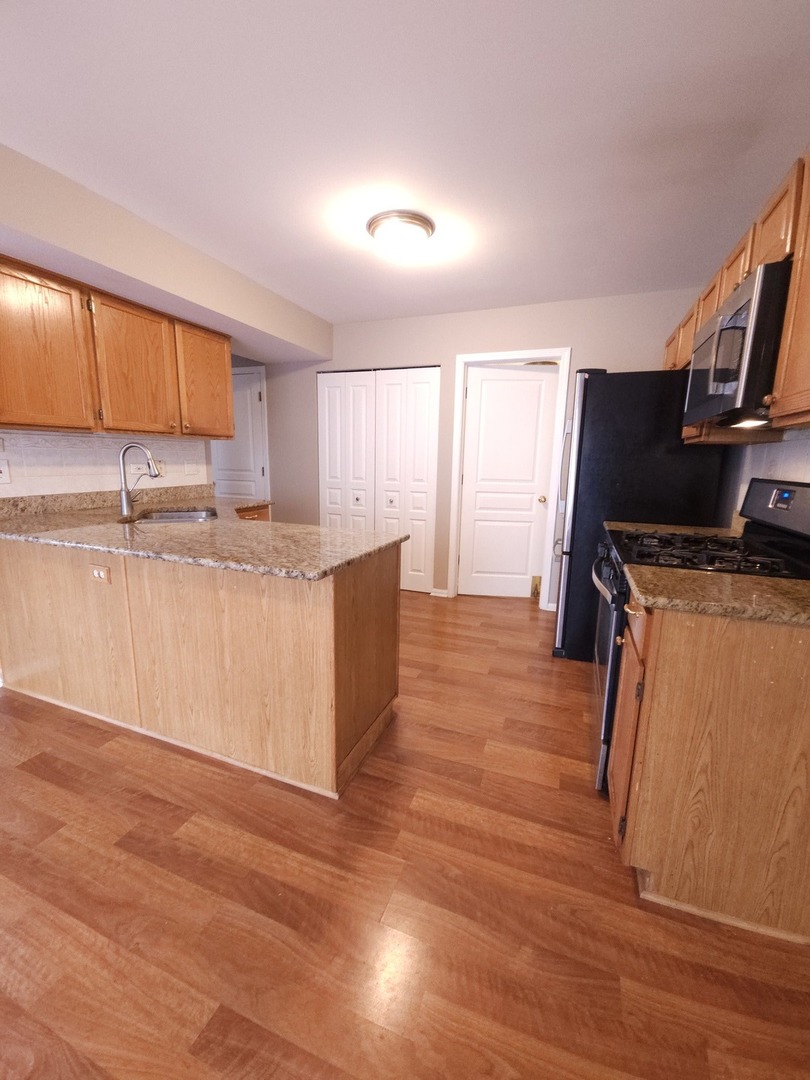 407 Spaulding Road, Unit 407 Bartlett, IL 60103 - Photo 7 of 18 a kitchen with stainless steel appliances granite countertop a sink a stove a refrigerator cabinets and wooden floor