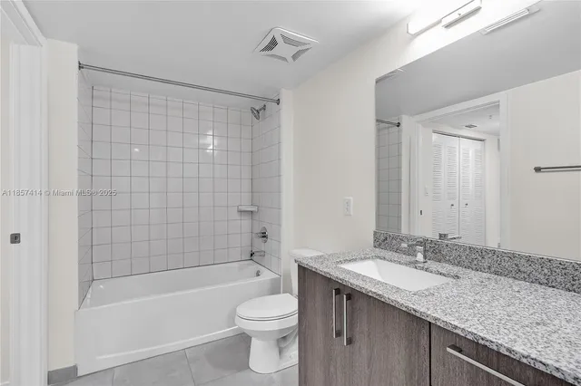 a bathroom with a granite countertop sink a toilet and shower