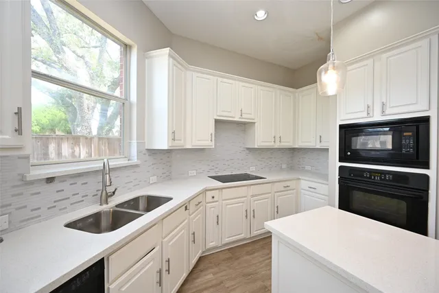 a kitchen with white cabinets appliances a sink and a window