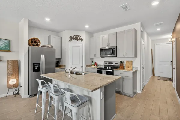 a kitchen with stainless steel appliances granite countertop a table chairs sink refrigerator and microwave