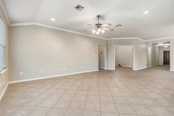 an empty room with white walls and chandelier fan