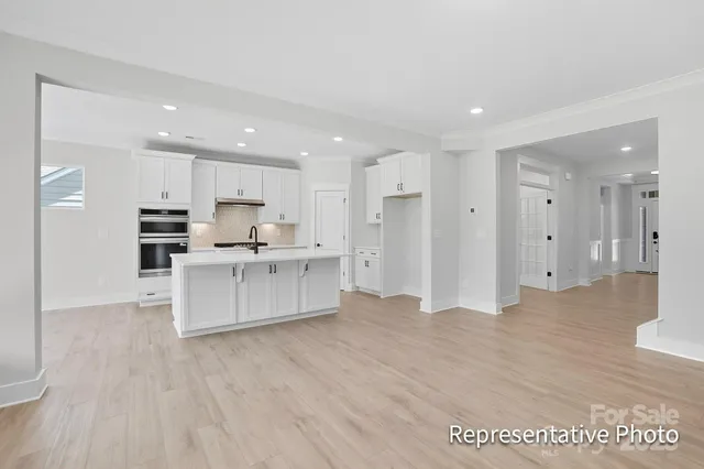 a large white kitchen with kitchen island a sink a stove a refrigerator and white cabinets