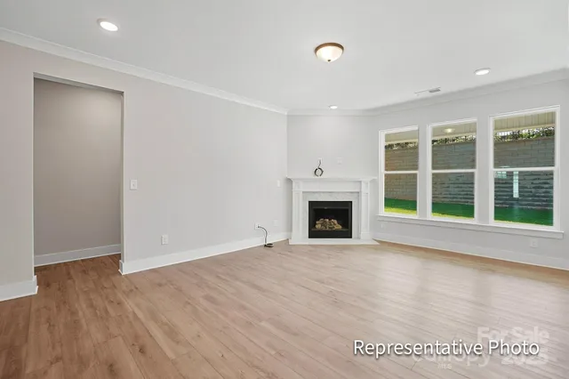 an empty room with wooden floor fireplace and windows