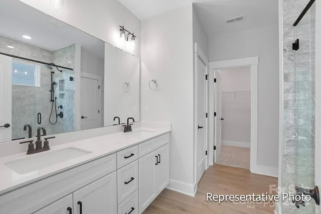 a spacious bathroom with a double vanity sink a mirror and a shower
