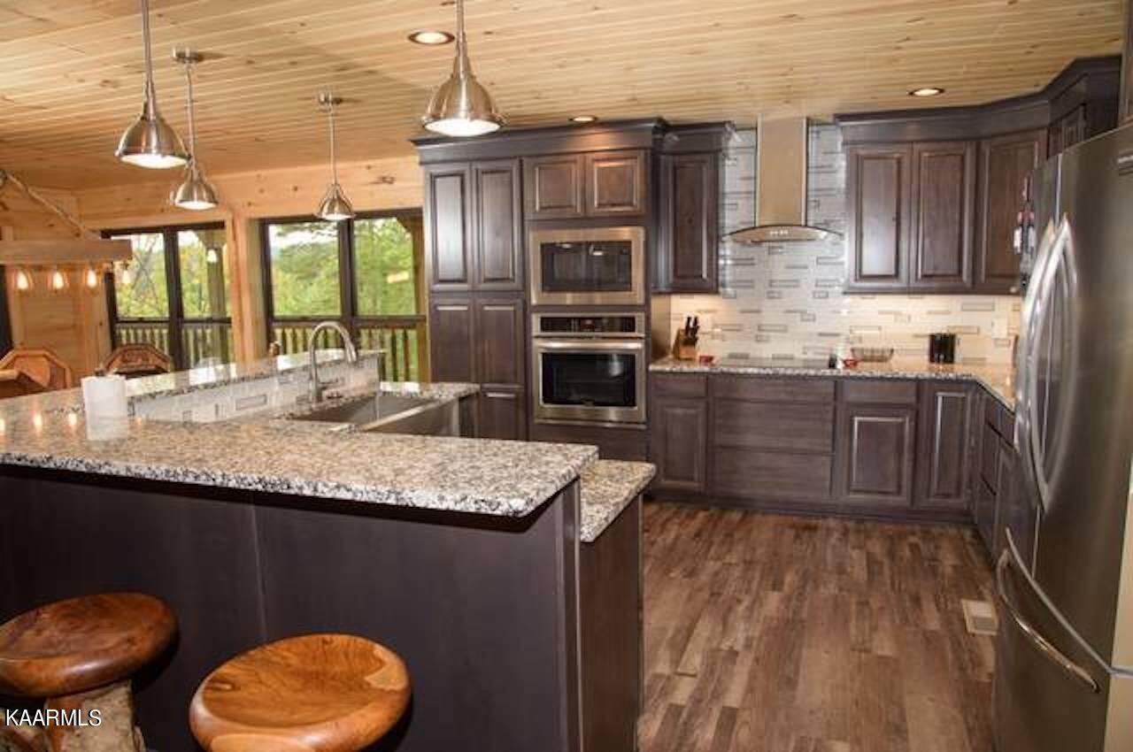 2252 Coopers Hawk Way Sevierville, TN 37862 - Photo 20 of 56 a kitchen with granite countertop a stove a sink and a wooden cabinets