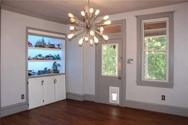 a view of an empty room with wooden floor and window