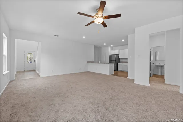 a view of a livingroom with a ceiling fan and kitchen view