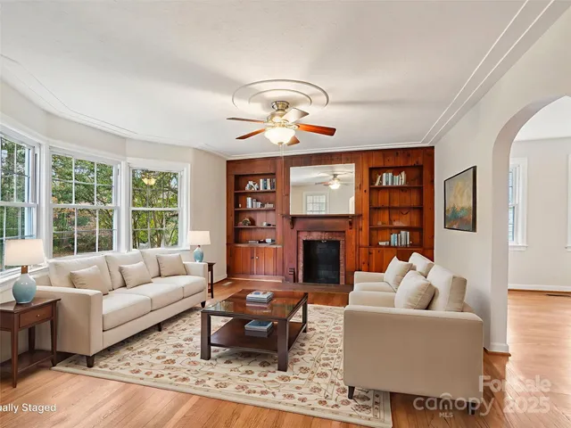 a living room with furniture a fireplace and a floor to ceiling window