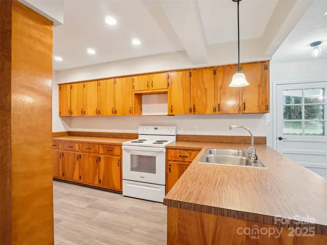 a kitchen with stainless steel appliances granite countertop a sink a stove and a wooden floors
