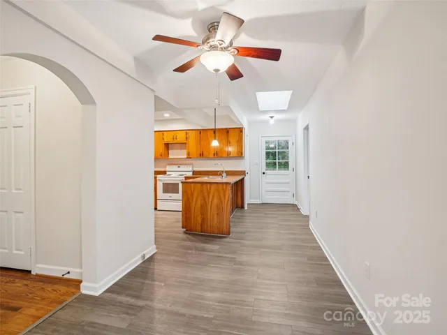 a view of a kitchen with wooden floor a sink a refrigerator and window