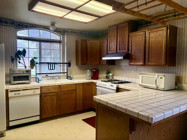 a kitchen with stainless steel appliances granite countertop a stove a sink dishwasher and a microwave oven with cabinets