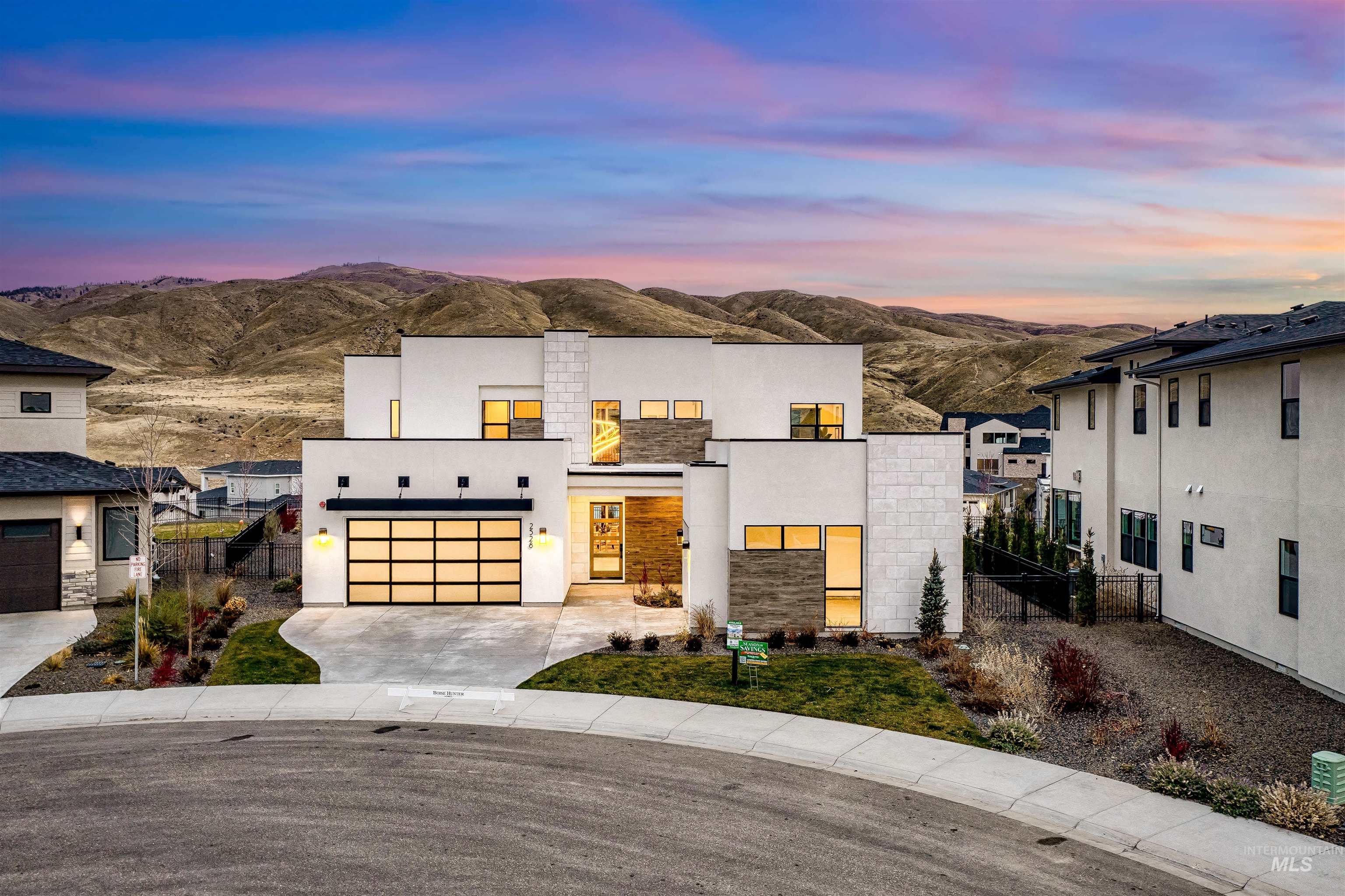 Modern home featuring concrete driveway, stucco siding, an attached garage, and a mountain view