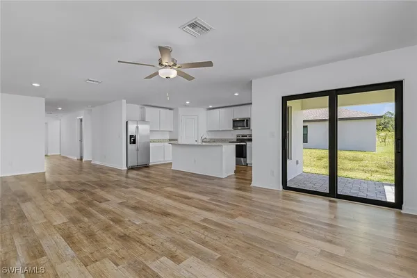a view of an empty room with window and wooden floor
