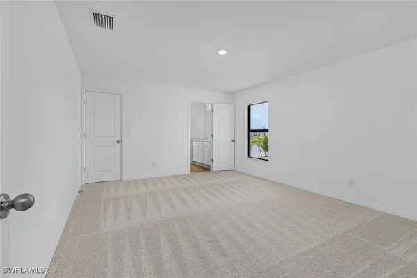 a view of an empty room with window and closet area