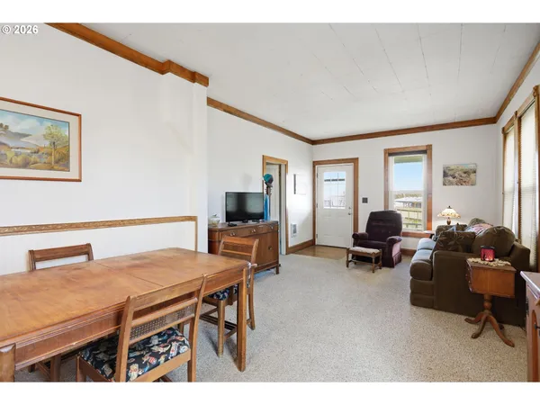a living room with furniture a flat screen tv and a refrigerator