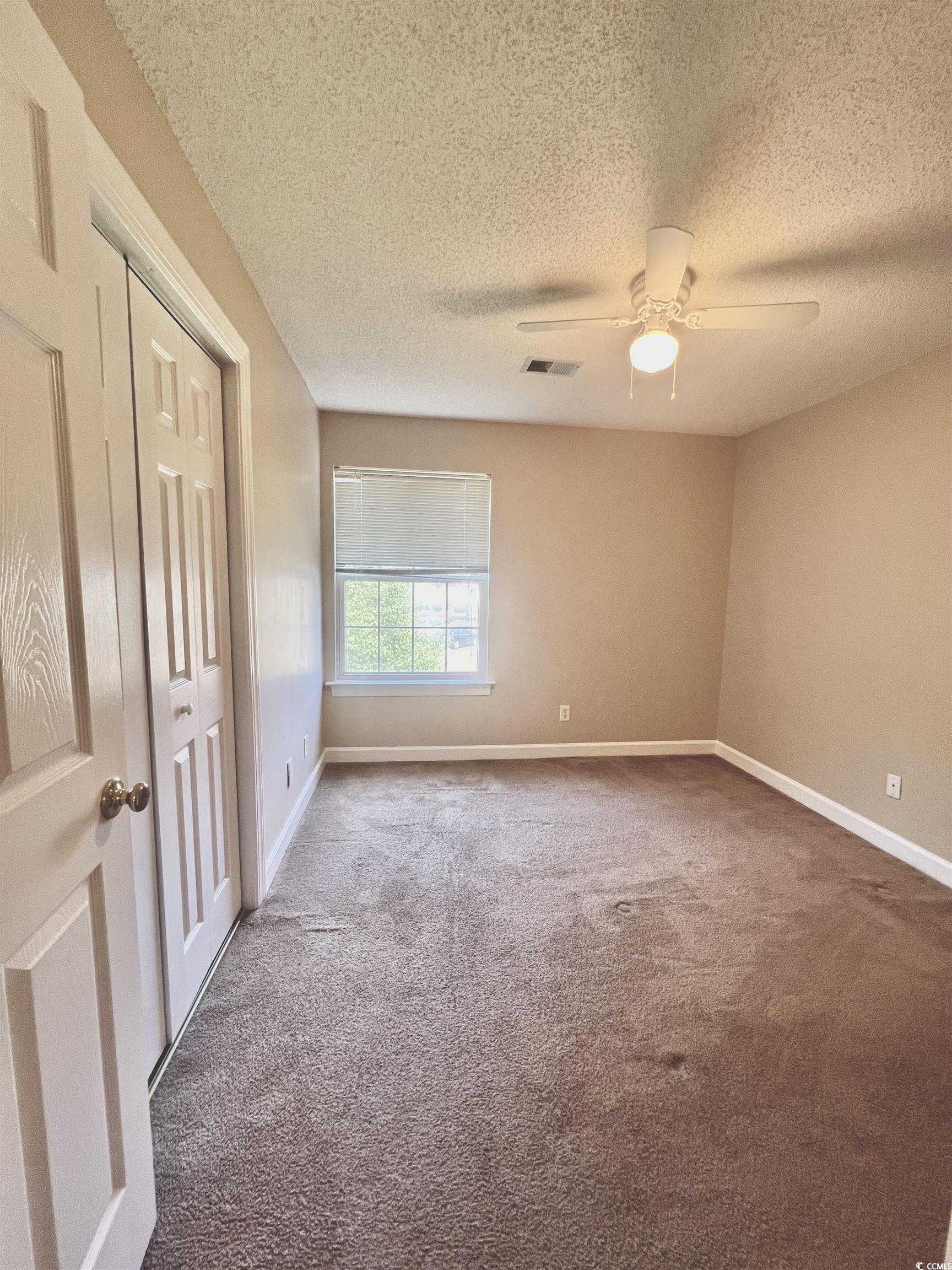 4394 Daphne Lane, Unit F Murrells Inlet, SC 29576 - Photo 15 of 40 Empty room with carpet floors, ceiling fan, baseboards, and a textured ceiling
