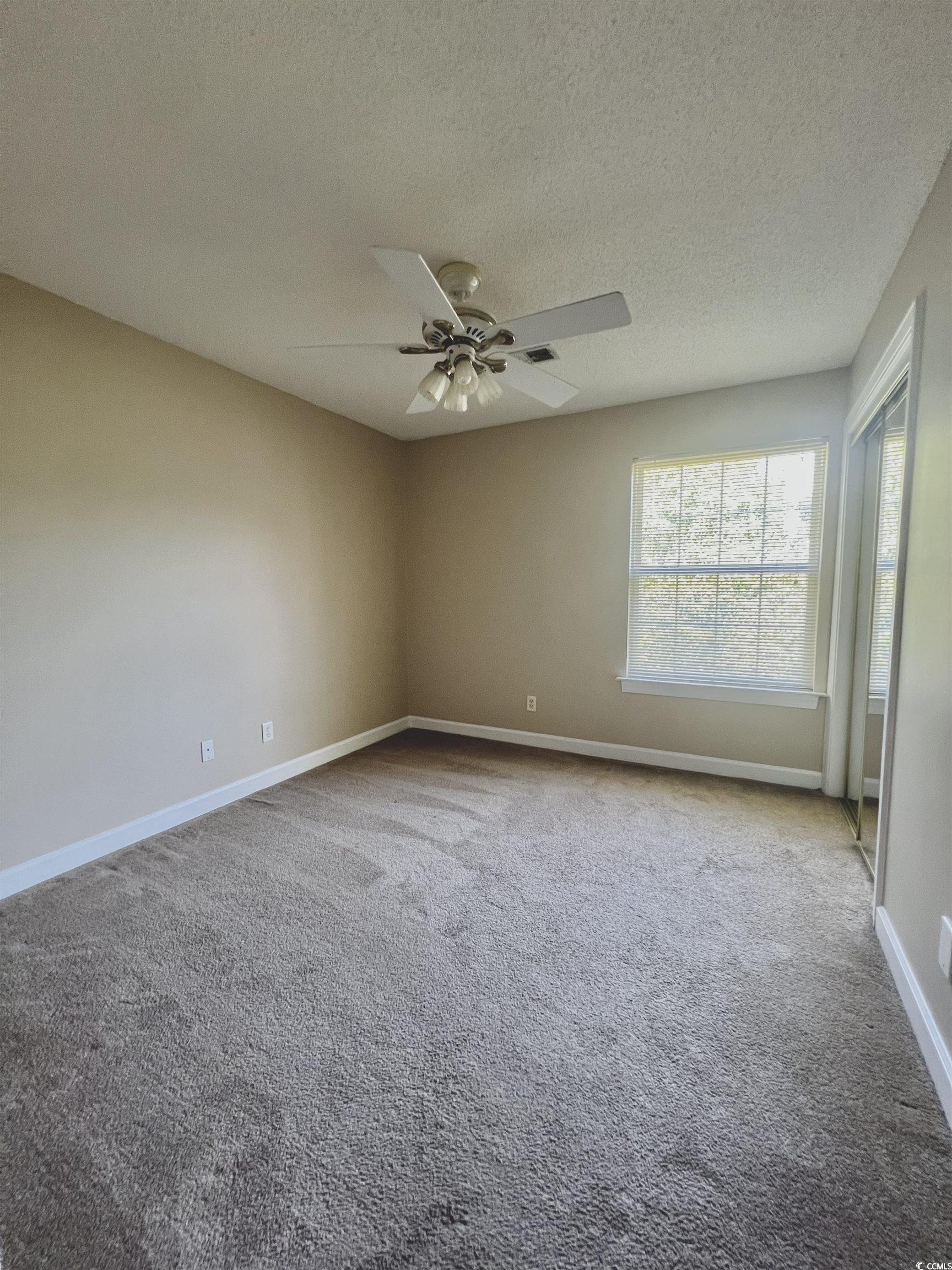 4394 Daphne Lane, Unit F Murrells Inlet, SC 29576 - Photo 18 of 40 Carpeted empty room with baseboards, a textured ceiling, and ceiling fan