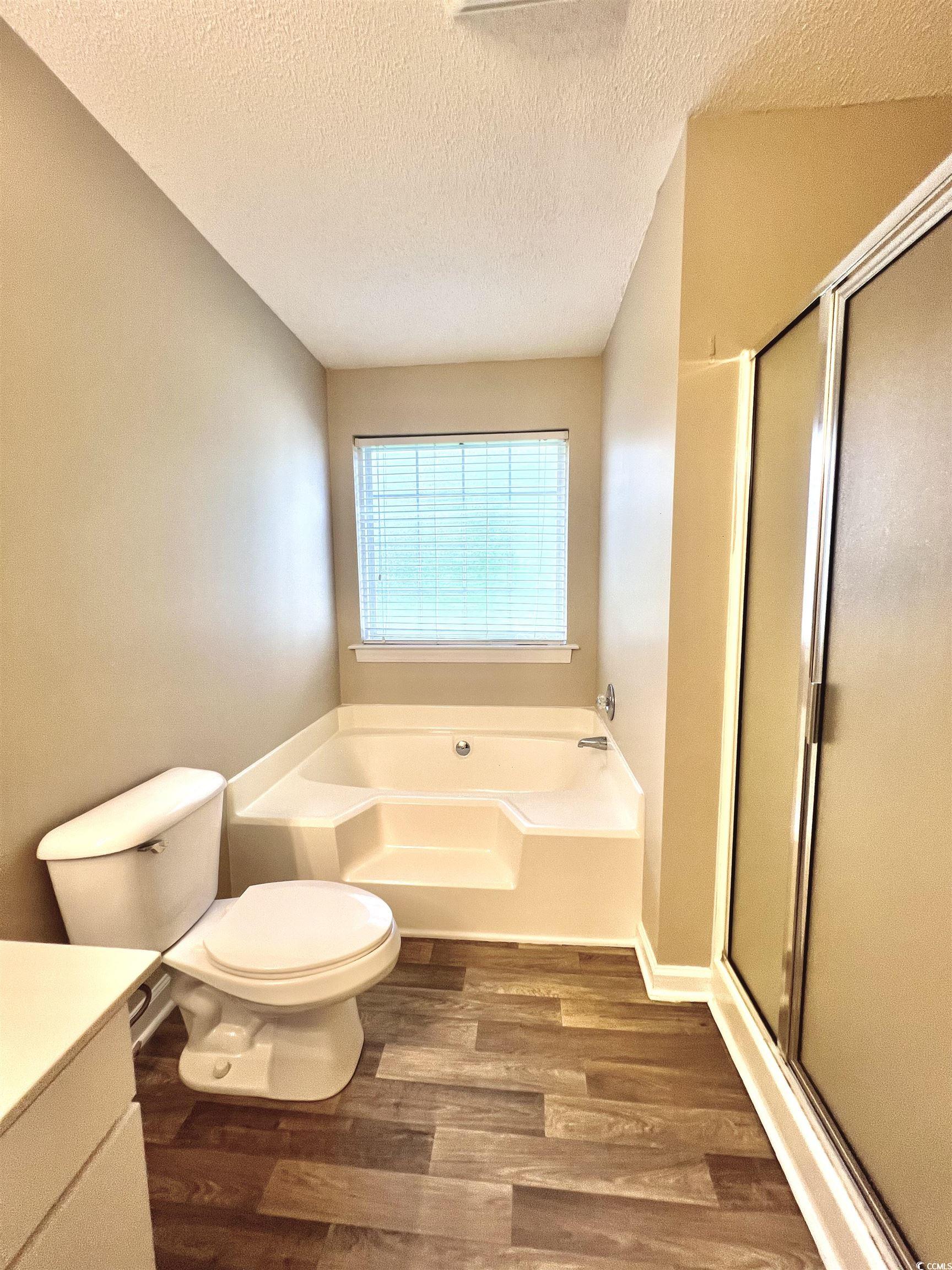 4394 Daphne Lane, Unit F Murrells Inlet, SC 29576 - Photo 27 of 40 Full bathroom featuring wood finished floors, a garden tub, a shower stall, toilet, and a textured ceiling