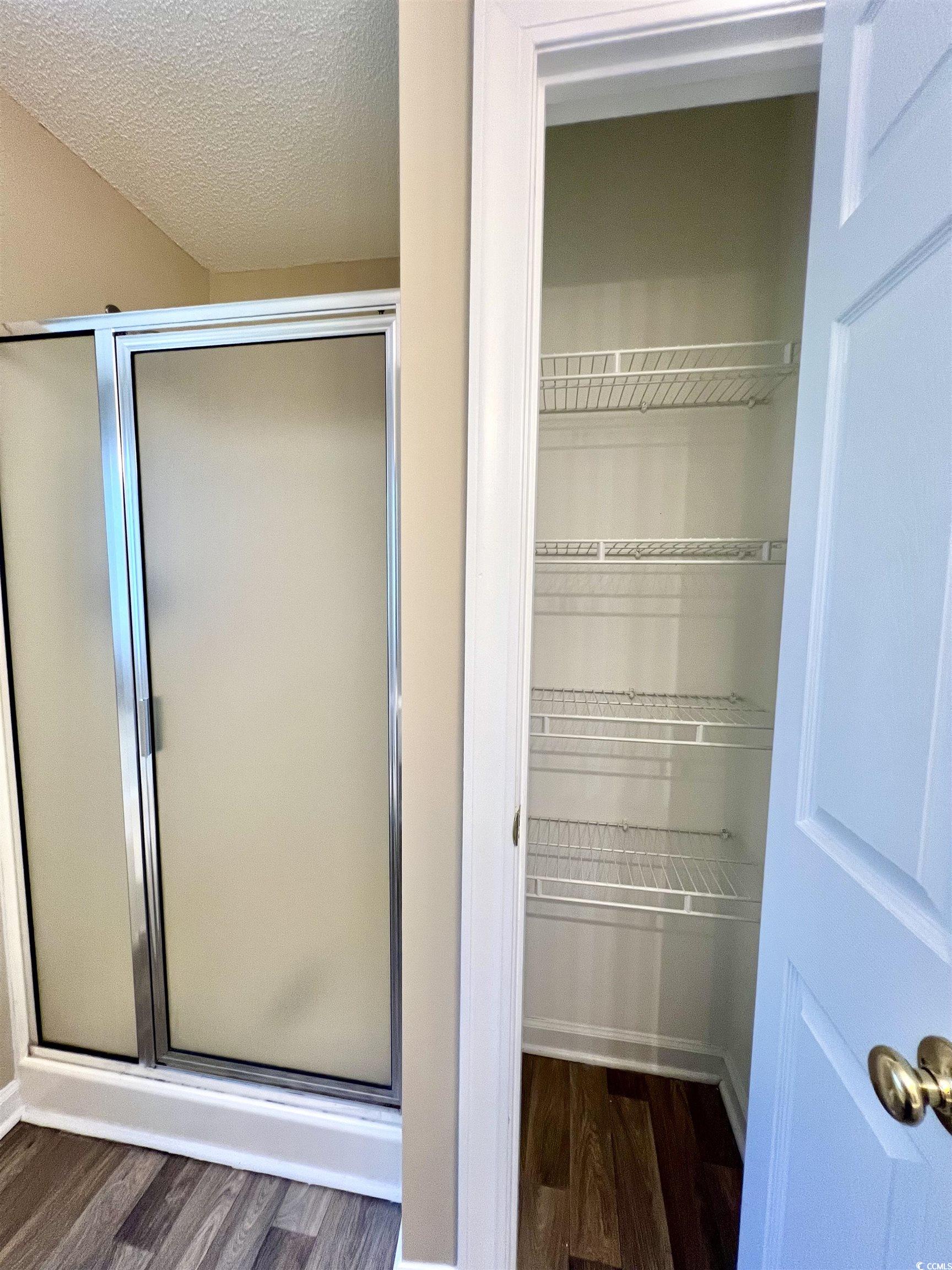 4394 Daphne Lane, Unit F Murrells Inlet, SC 29576 - Photo 28 of 40 Full bathroom featuring wood finished floors, a stall shower, a walk in closet, and a textured ceiling