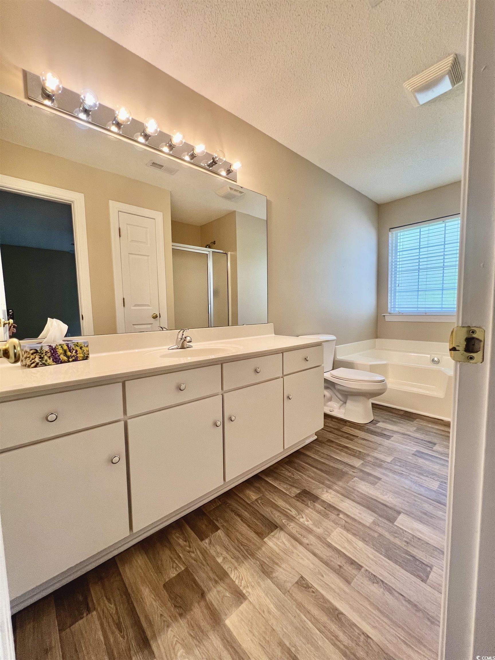 4394 Daphne Lane, Unit F Murrells Inlet, SC 29576 - Photo 31 of 40 Full bath featuring wood finished floors, vanity, a stall shower, a textured ceiling, and a bath