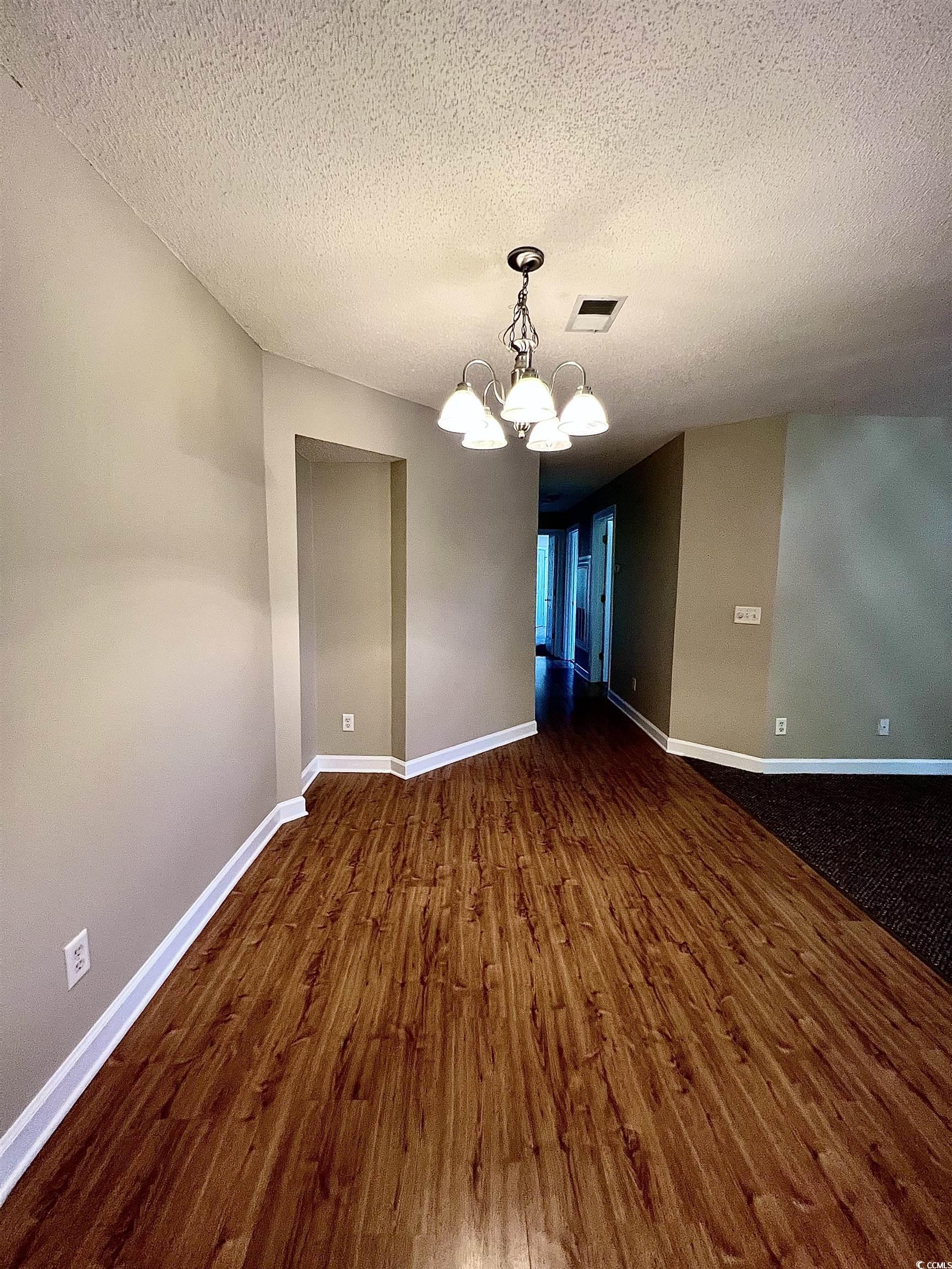4394 Daphne Lane, Unit F Murrells Inlet, SC 29576 - Photo 10 of 40 Unfurnished dining area featuring dark wood finished floors, a chandelier, a textured ceiling, and baseboards