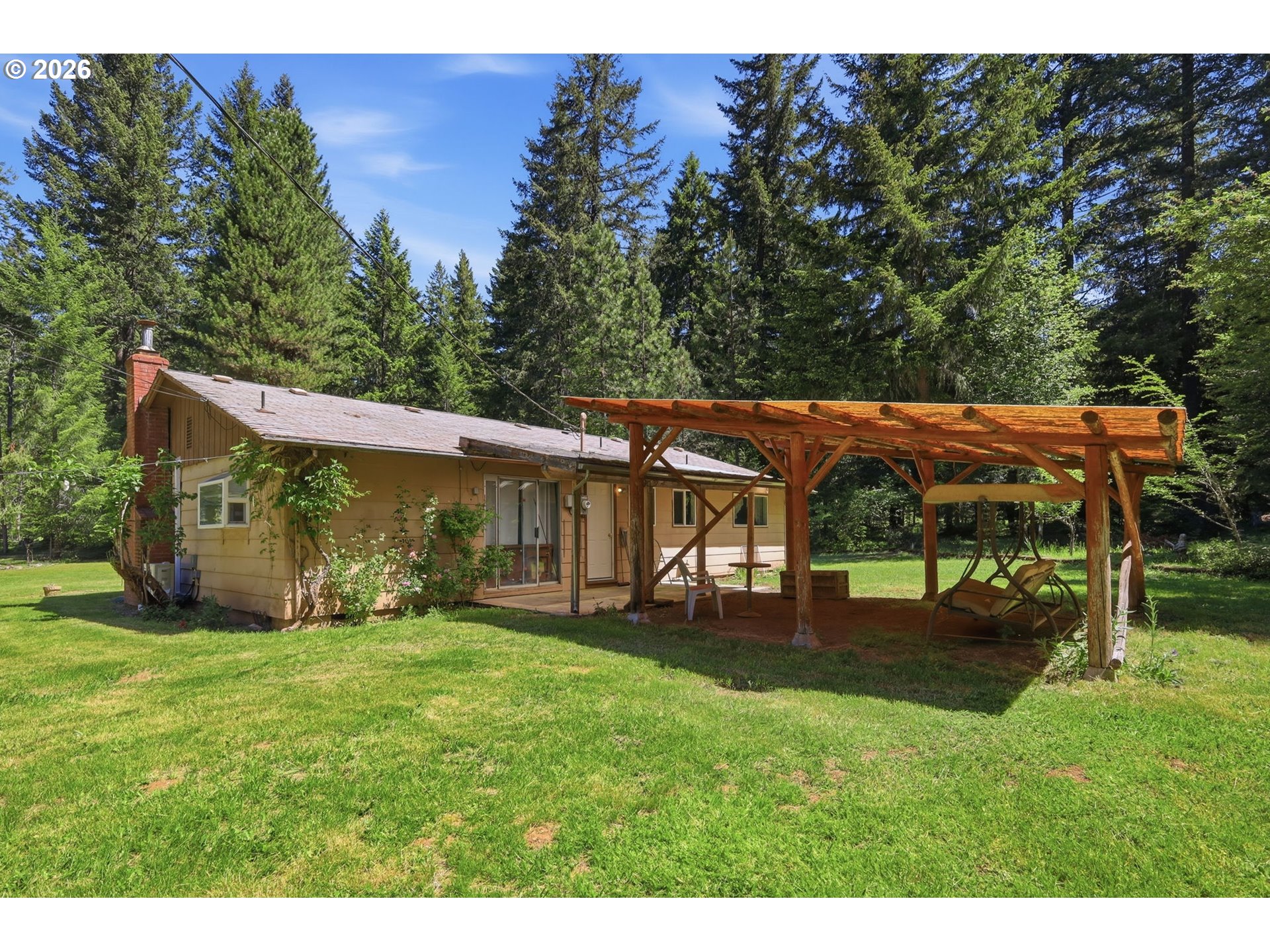 49782 Huckleberry Road Oakridge, OR 97463 - Photo 2 of 21 a view of a house with a big yard potted plants and large tree