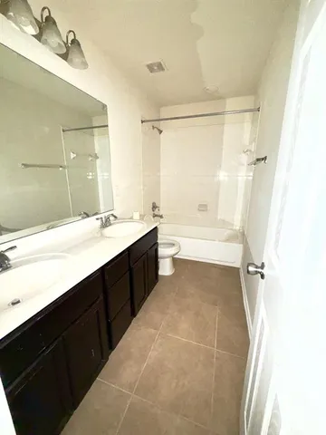 a bathroom with a bathtub shower sink vanity and mirror