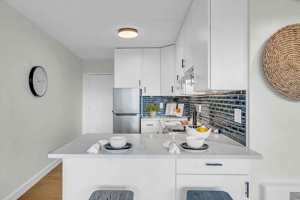 200 Swanton Street, Unit 502 Winchester, MA 01890 - Photo 5 of 24 a kitchen with a sink a stove and white cabinets with wooden floor