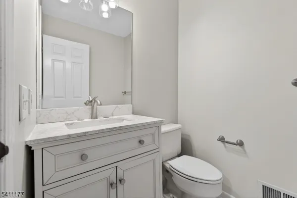 a bathroom with a granite countertop toilet sink mirror and vanity