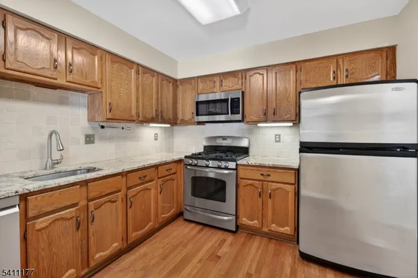 a kitchen with stainless steel appliances granite countertop a refrigerator stove and sink