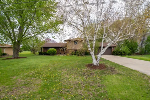 a view of a house with a yard and large trees