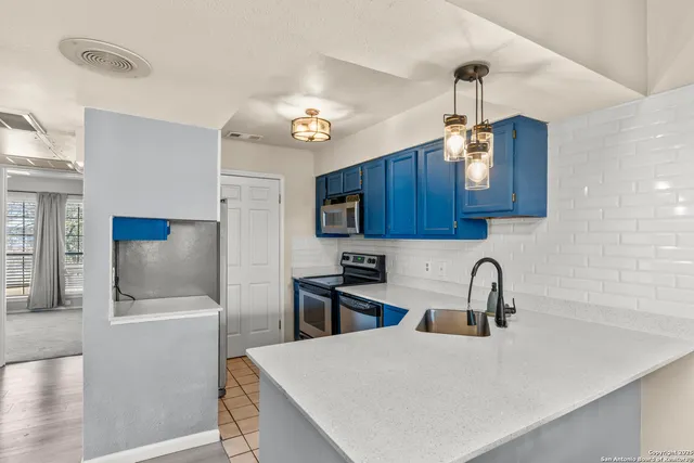 a kitchen with stainless steel appliances a sink a microwave a refrigerator and cabinets