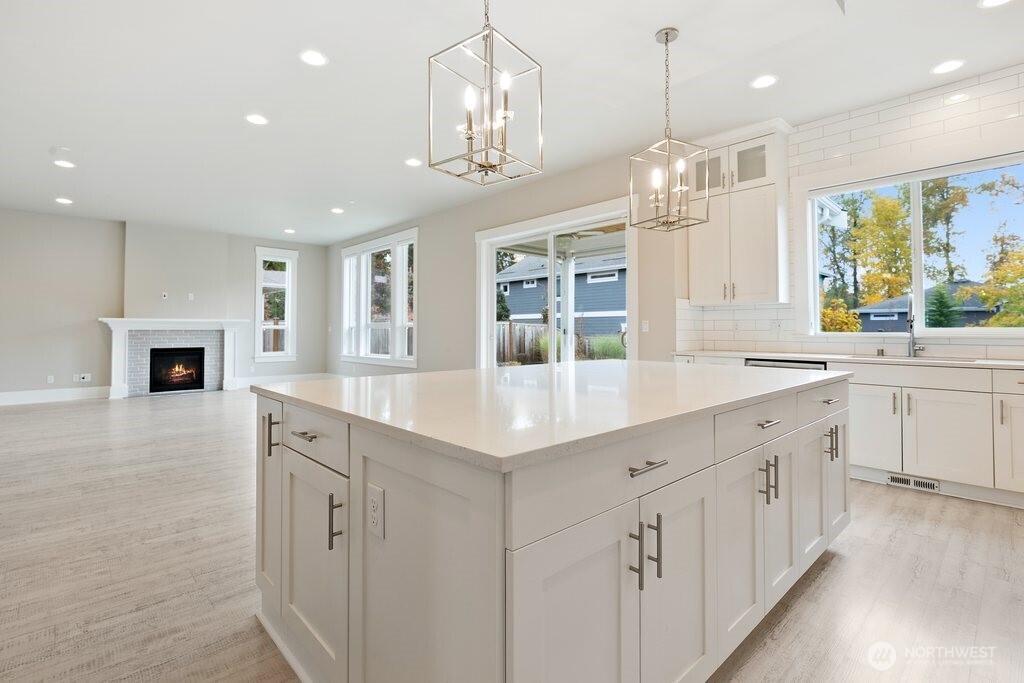 11575 Southeast 81st Street Newcastle, WA 98056 - Photo 11 of 40 a large white kitchen with granite countertop a stove top oven a sink a dishwasher and a dining table with wooden floor