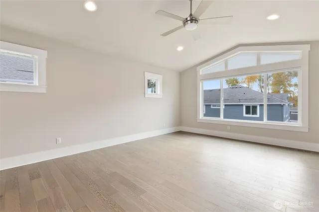 an empty room with chandelier fan and windows