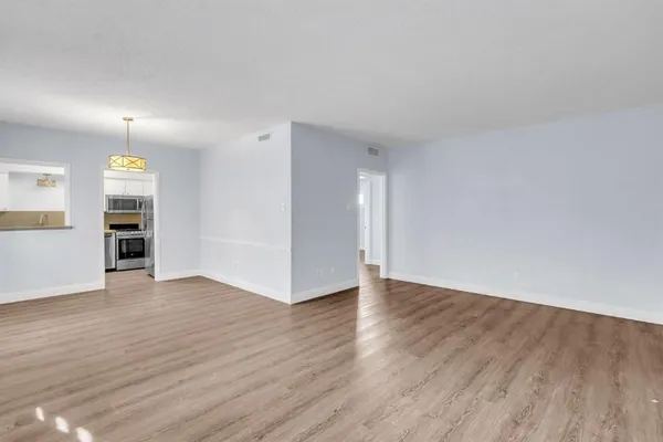 an empty room with wooden floor closet and windows