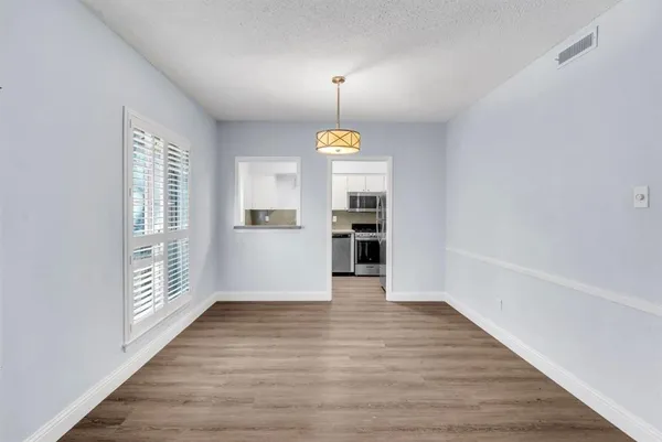 a view of an empty room with window and wooden floor