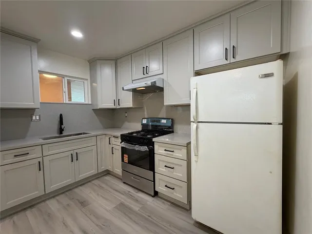 a kitchen with cabinets appliances and wooden floor