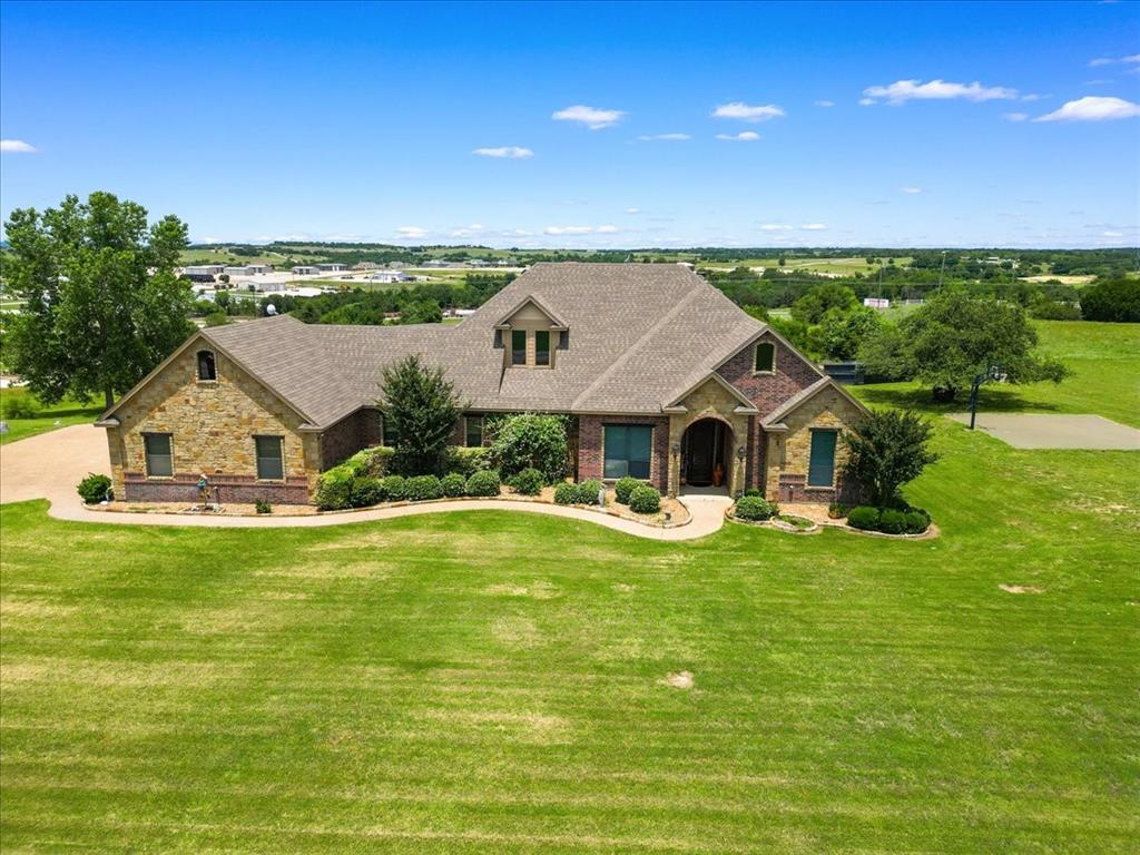 View of front of house featuring a front yard, brick siding, a shingled roof, and stone siding. Side entry 3 ar garage.