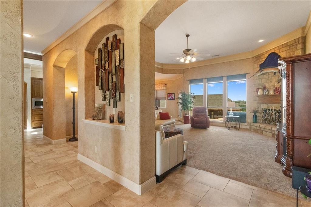 120 Trail Ridge Weatherford, TX 76087 - Photo 14 of 37 View of living area from entry foyer, Tiled living area with windows open to viewing of back yard, with arched walkways, ceiling fan, carpet flooring