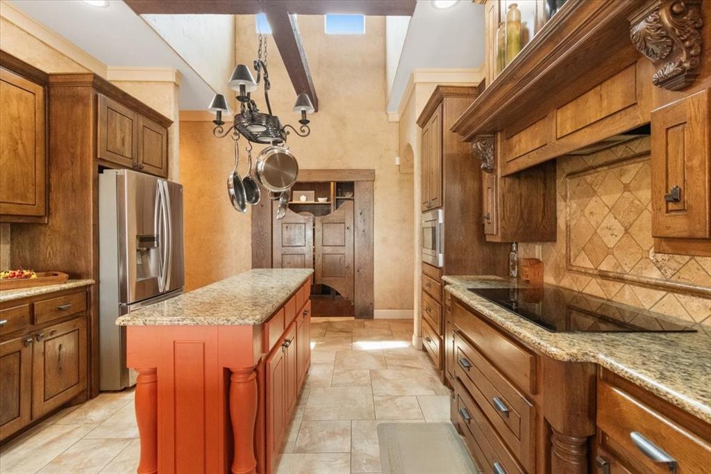 120 Trail Ridge Weatherford, TX 76087 - Photo 21 of 37 Kitchen with black electric flat top stove, oven, microwave, pots and pan drawers, and pot and pan rack above island , tasteful backsplash