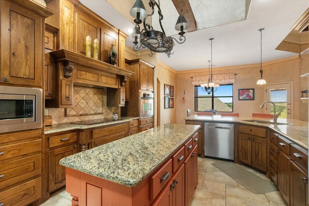 120 Trail Ridge Weatherford, TX 76087 - Photo 26 of 37 Kitchen featuring island and pot and pan rack, double under counter sink, appliances with stainless steel finishes, a kitchen island, and decorative backsplash