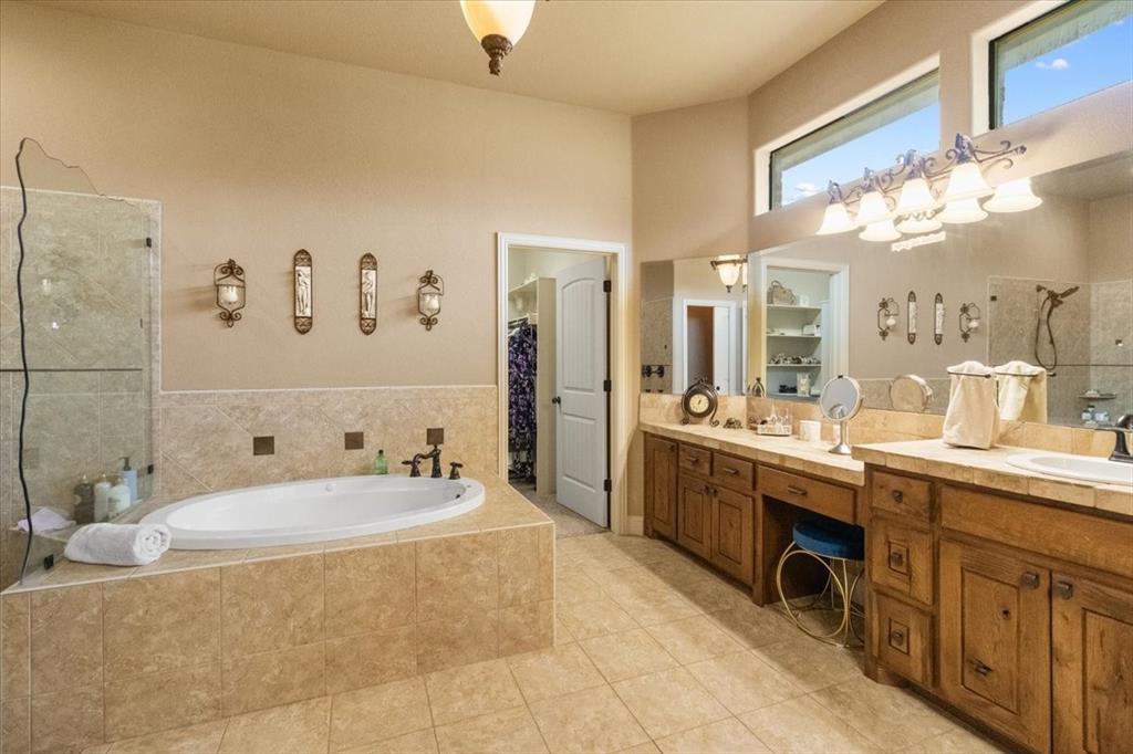 120 Trail Ridge Weatherford, TX 76087 - Photo 32 of 37 Primary Bathroom with tiled shower,double shower heads, custom glass half wall, tile patterned floors, double vanity, knee space vanity area, jetted tub