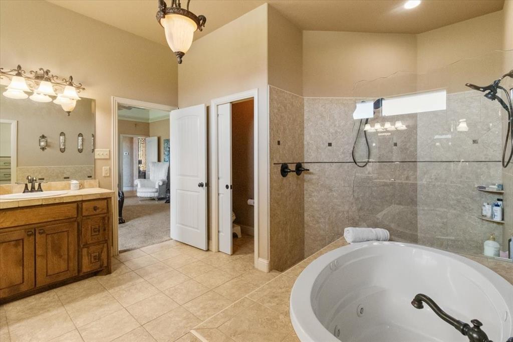 120 Trail Ridge Weatherford, TX 76087 - Photo 33 of 37 Primary Bath with jetted tub, double vanities and separate knee space vanity, double headed shower, a walk in shower, toilet with pocket door, and tile patterned flooring