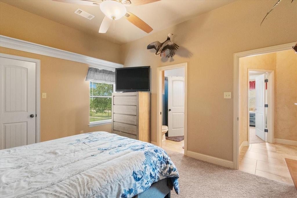 120 Trail Ridge Weatherford, TX 76087 - Photo 36 of 37 Bedroom with walk in closet, light carpet, connected bathroom, ceiling fan, and light tile patterned floors