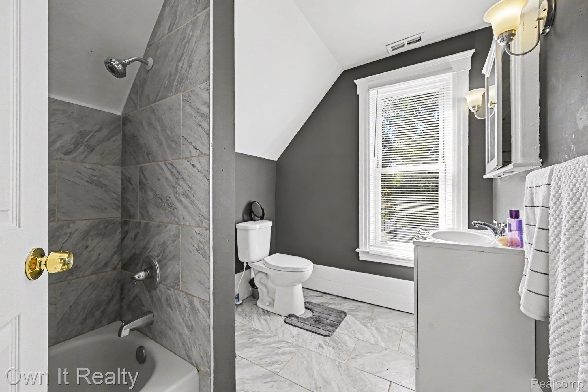 44 Maple Street River Rouge, MI 48218 - Photo 20 of 33 Tub and shower combination with gray tile surround, white single vanity with integrated sink, and wall-mounted medicine cabinet