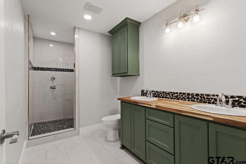 2819 New Copeland Road Tyler, TX 75701 - Photo 20 of 39 a bathroom with a granite countertop sink a toilet and shower