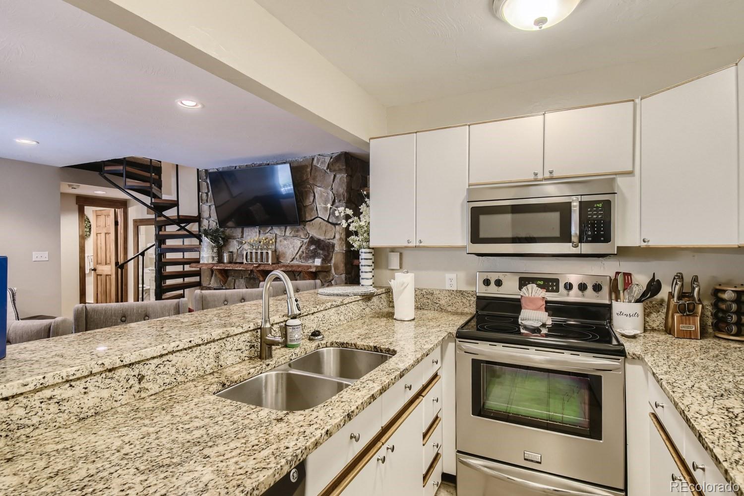 1937 Soda Ridge Road, Unit 1153/1154 Dillon, CO 80435 - Photo 5 of 17 a kitchen with stainless steel appliances granite countertop a sink and a stove top oven with wooden floor